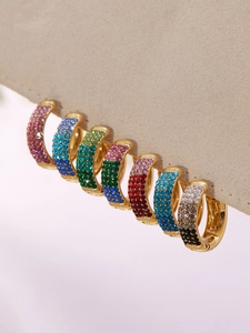 Macro shot of seven gold hoops set with colorful cubic zirconia on a beige card