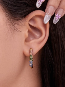 Detailed close-up of long U-shaped gold earrings with colorful gradient 5A zircons on ear
