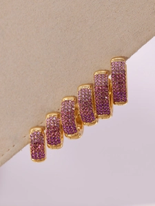 Detailed close-up of gold huggie earrings set with gradient purple cubic zirconia