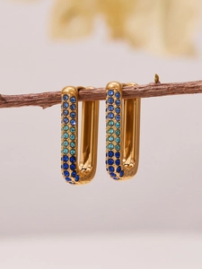 U-shaped gold-plated earrings with gradient blue cubic zirconia on a wooden branch