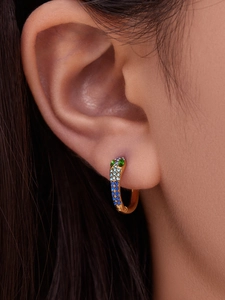 Close-up of gold U-shaped earrings with gradient colorful cubic zirconia on ear