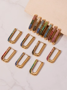 Detail of 18k gold plated U-shaped earrings with colorful zircon stones on marble