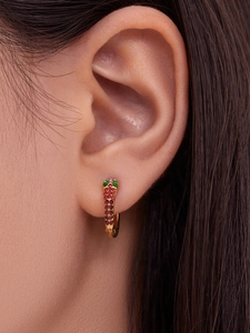 Macro view of a 18k gold plated U-shaped snake earring with red and green zircons