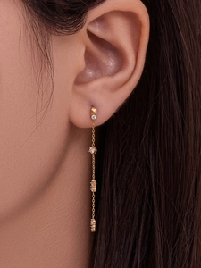 Détail de boucles d'oreilles à longue chaîne dorée 18k avec zircone cubique sur le mannequin