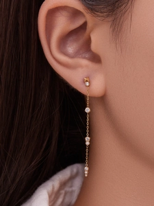 Macro de boucles d'oreilles à pompons en or 18 carats avec cristaux de zircon sur l'oreille