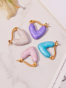 Detailansicht von vier herzförmigen Ohrringen in Weiß, Violett, Rosa und Blau mit Vergoldung