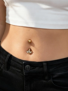 Detail shot of a gold belly ring with three marquise cut crystals on a model's navel