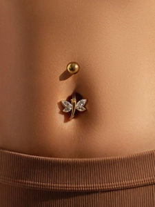 Macro detail of dragonfly navel ring with marquise-cut zircons and gold plating on skin