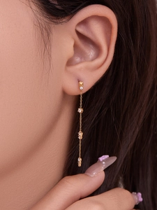 Détail des boucles d'oreilles à pompons plaquées or 18 carats avec zircons sur modèle