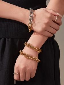 Gros plan de bracelets à maillons dorés et de bagues micro-pavées sur mains de mannequin