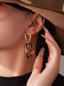 Detailed close-up of vintage resin drop earrings with tortoiseshell texture and gold finish