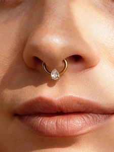 Close-up of titanium septum ring with pear-shaped zircon on a model's nose