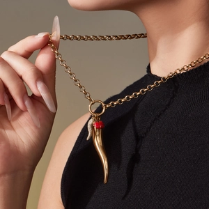Gold cornicello pepper pendant necklace with red enamel and crystals on a female model