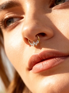Macro view of gold septum ring featuring five marquise-cut zircons on a female model