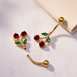 Piercing de ombligo de cereza dorada con circonitas rojas y verdes en mármol