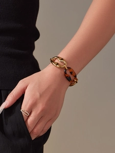 Detail of vintage gold chain bracelet with tortoiseshell resin links and a dainty ring