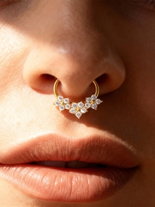 Close-up of gold titanium septum ring with 5A zircon clusters on a fashion model