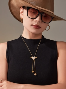 Detail of gold heart wing Y-shaped necklace with cubic zirconia and tassel on model