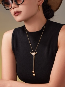 Close-up of golden winged heart necklace with zircon and matching ripple hoop earrings