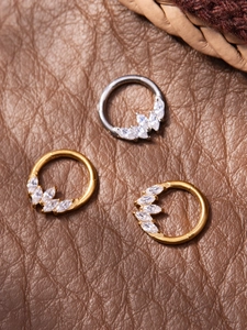 Macro shot of titanium nose rings featuring five marquise-cut zircons in gold and silver