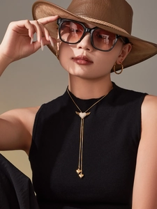 Detail view of golden heart and wing bolo necklace worn by a model in luxury style
