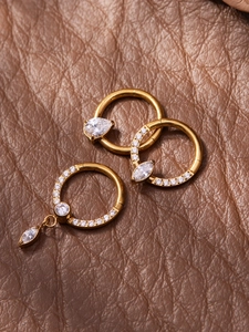 Detailed close-up of gold titanium nose rings with pear and marquise-cut 5A zircons