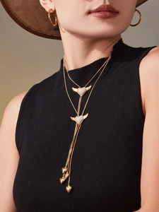 Detail of gold winged heart necklace and hoop earrings set on black knitwear