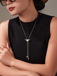 Macro detail of adjustable heart wing necklace with zirconia inlay on a black outfit