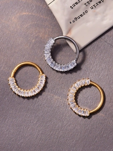 Macro detail of titanium clicker nose rings with baguette-cut zircon in gold and silver