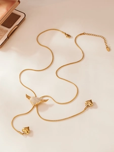 Close-up of golden winged heart necklace with zircon pavé and dangling tassels