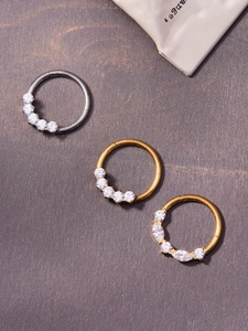 Detailed view of titanium nose rings with inlaid 5A zircons in silver and gold finishes