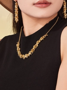 Macro detail of gold-plated cluster texture on minimalist necklace and earrings set