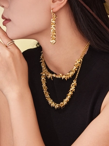 Close-up of a model wearing double-layered gold heart pendant necklace and drop earring