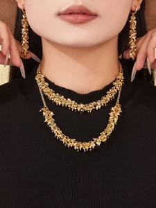 Detail of double-layer gold necklace and long drop earrings with clustered metal texture