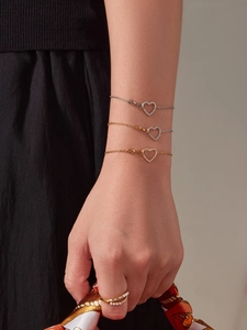 Dettaglio di bracciali a cuore con zirconi e anello di perle in finitura oro e argento