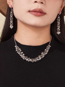 Detailed view of polished silver heart-shaped pendant necklace and matching long earrings