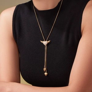 Adjustable gold heart wing necklace with sparkling zircons worn on black knitwear