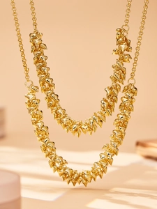 Detailed view of layered gold chain necklace featuring multiple polished spike charms