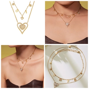 Detail of double-layer gold necklace with heart and tree of life charms and zircon