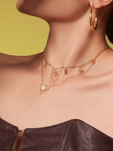 Close-up of layered gold heart necklace and textured large hoop earrings on a model