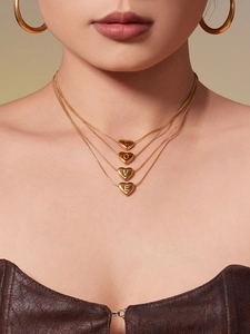 Detail of layered gold necklaces with heart pendants engraved with LOVE letters and hoop earrings