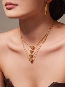 Detail of 4-layer gold snake chain necklace with heart pendants spelling LOVE