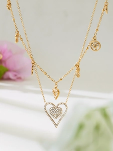 Close-up of double-layer gold necklace featuring heart pendants and sparkling zircon stones