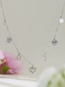Detail of silver double layer necklace with heart, butterfly and clover charms