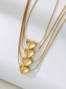 Close-up of golden snake chain necklace with heart pendants engraved with LOVE