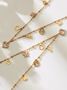 Detailed close-up of 18k gold plated chains with heart, butterfly and clover charms