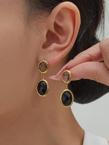 Detail of 18k gold plated earrings featuring oval black faceted stone and brown gem