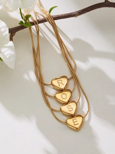 Detail of 18k gold heart pendants on a snake chain spelling the word ROSE in macro