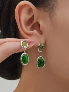 Close-up of green oval faceted glass stone earrings on a model showing refined elegance