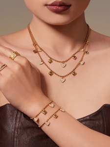 Close-up of a gold-plated heart pendant necklace and bracelet set worn by a model